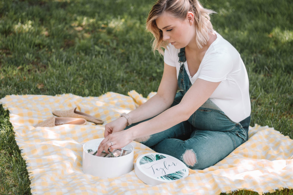 Taylor sitting on. a picnic blanket with a box of makeup powders